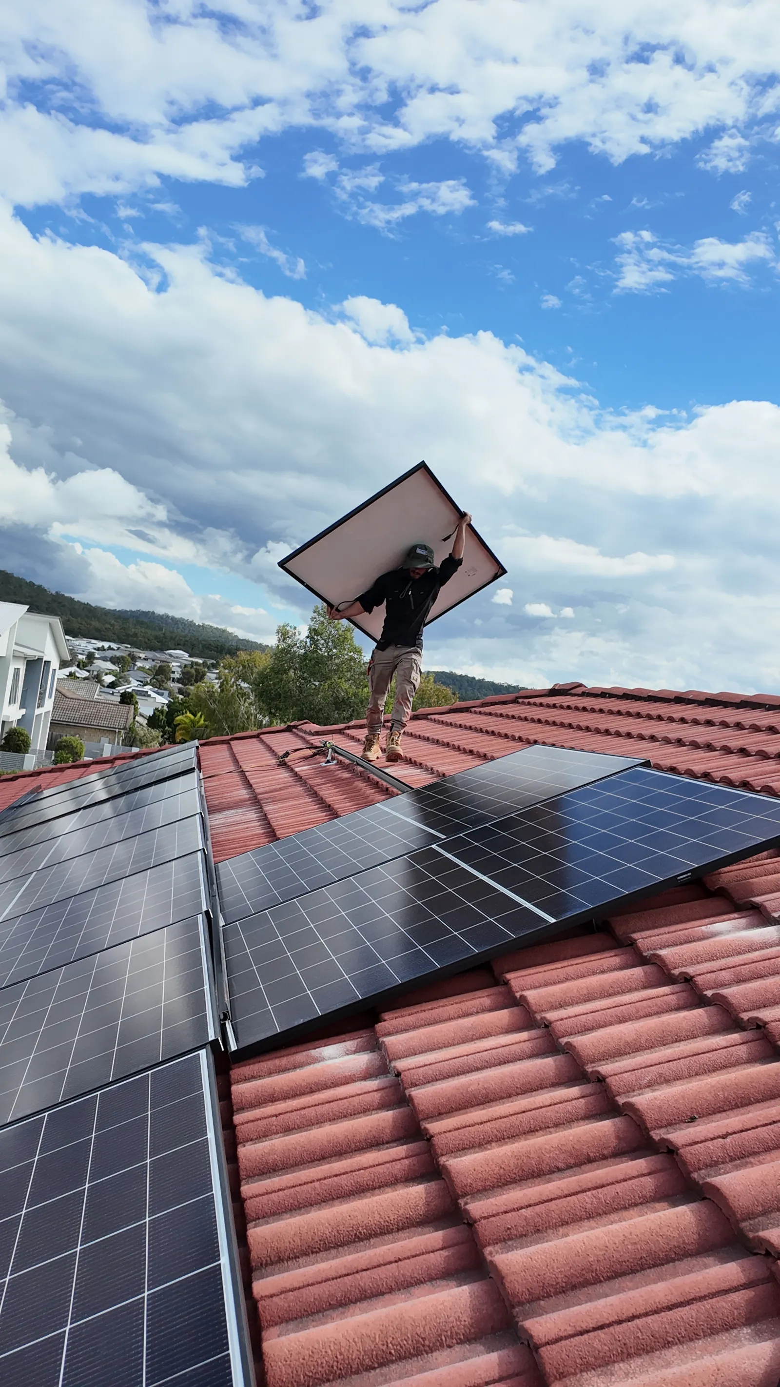 Worth Solar Group installer carrying a panel across a tiled roof